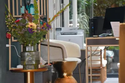 a vase of flowers on a table with a chair at The LIF Boutique in Amsterdam