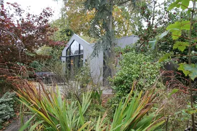 a glass house in a garden with plants at De Bosuil in Bergen