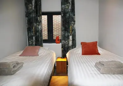 two twin beds in a room with a window at De Bosuil in Bergen