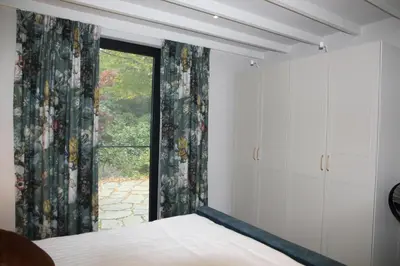 a bedroom with a bed and a large window at De Bosuil in Bergen