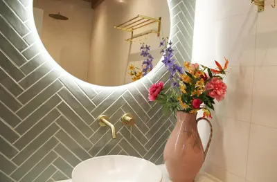 a vase with flowers on a bathroom counter with a mirror at De Bosuil in Bergen