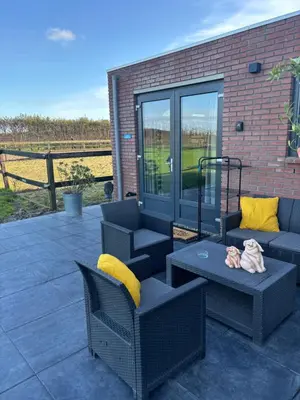 a patio with two chairs and a couch and a table at DE WEELEN met Jacuzzi en of Zwembad Topkeuze Romantiek in Lutjebroek