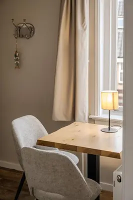 a table and chairs with a lamp and a window at Short Stay Zandvoort in Zandvoort