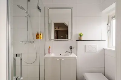 a white bathroom with a sink and a shower at Short Stay Zandvoort in Zandvoort
