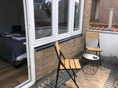 a patio with two chairs and a bench next to a window at Short Stay Zandvoort in Zandvoort