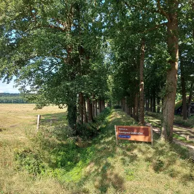 a sign in the grass next to a group of trees at Bed & Breakfast Puur Natuur Putten, met privé sauna in Putten