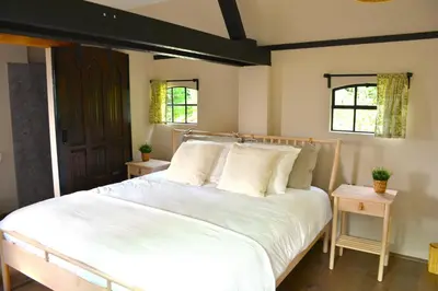 a bedroom with a white bed and two windows at Bed & Breakfast Puur Natuur Putten, met privé sauna in Putten