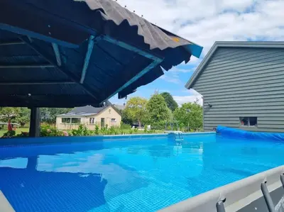 a large blue swimming pool with a blue umbrella at Luxe vrijstaand gastenverblijf - landelijk gelegen in IJsselstein