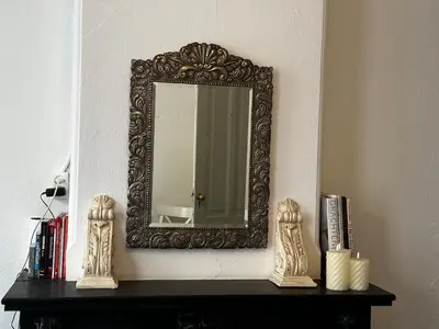 a mirror on a wall above a table with books at De Stijlkamer in Amsterdam