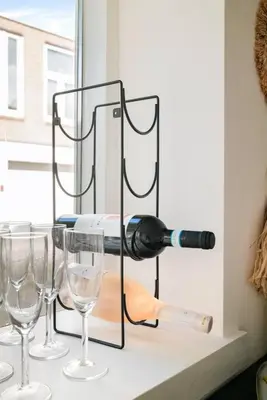 a bottle of wine on a shelf with three wine glasses at Chique Ibiza Zaandam in Zaandam