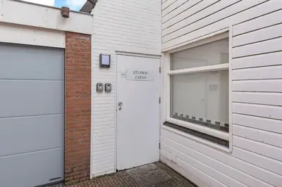 a white house with two garage doors and a window at Zaras Studio Hermes in Zandvoort