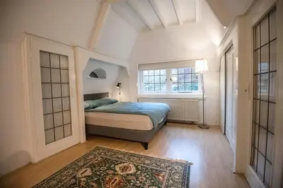 a bedroom with a bed and a window and a rug at Natuurhuis in het Gooi in Naarden