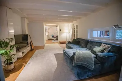 a living room with a blue couch and a television at Natuurhuis in het Gooi in Naarden