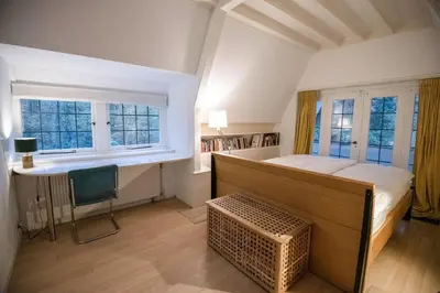a bedroom with a bed and a desk and windows at Natuurhuis in het Gooi in Naarden