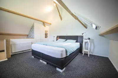 a bedroom with a large bed in a attic at B&B Louisehoeve in Linschoten