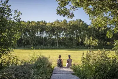 a group of three people sitting on a wooden walkway at B&B Louisehoeve in Linschoten