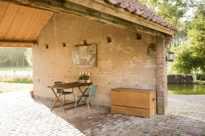 a table and chairs in a pavilion with a table and a wooden cabinet at B&B Louisehoeve in Linschoten