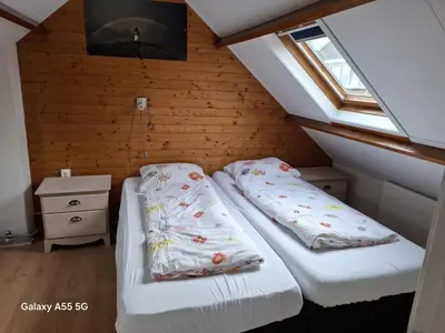 two beds in a small room with a window at De Stormmeeuw in Egmond aan Zee