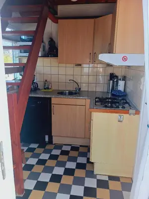 a kitchen with wooden cabinets and a checkered floor at De Stormmeeuw in Egmond aan Zee