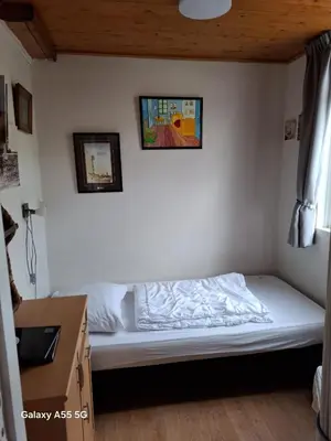 a small bedroom with a bed in the corner at De Stormmeeuw in Egmond aan Zee