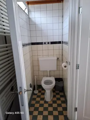 a small bathroom with a toilet and a checkered floor at De Stormmeeuw in Egmond aan Zee