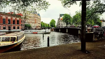 a river with boats and buildings and a bridge at Hotel The Bird in Amsterdam