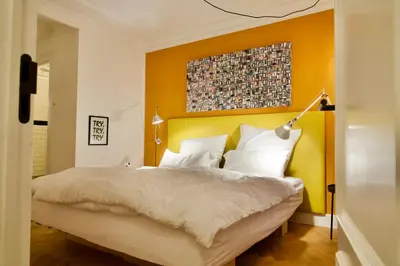 a bedroom with a bed with an orange wall at Banzai City Amsterdam in Amsterdam