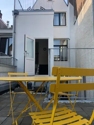 a yellow picnic table and two chairs in front of a building at Banzai City Amsterdam in Amsterdam