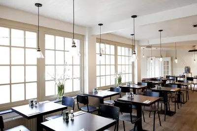a dining room with tables and chairs and windows at College Hotel Alkmaar in Alkmaar