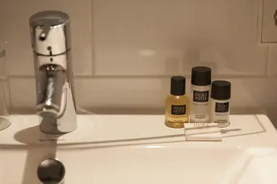 a bathroom sink with three bottles of moisturizers on it at College Hotel Alkmaar in Alkmaar