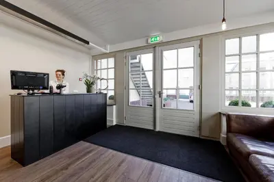 a woman standing at a counter in a room with a tv at College Hotel Alkmaar in Alkmaar