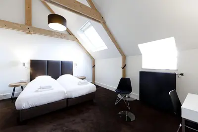 a bedroom with a bed and a desk and a window at College Hotel Alkmaar in Alkmaar