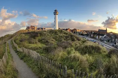 a lighthouse on top of a hill with a fence at Apartments Four Seasons Voorstraat in Egmond aan Zee