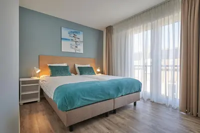 a bedroom with a large bed and a large window at Apartments Four Seasons Zuiderstraat in Egmond aan Zee