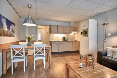 a kitchen and living room with a table and chairs at Apartments Four Seasons Zuiderstraat in Egmond aan Zee