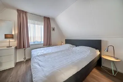 a bedroom with a large bed and a window at Apartments Four Seasons Zuiderstraat in Egmond aan Zee