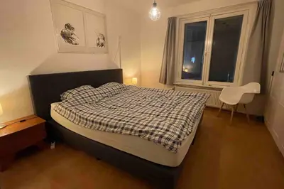 a bedroom with a bed and a chair and a window at Centre Hilversum, 20 minutes train to Amsterdam in Hilversum