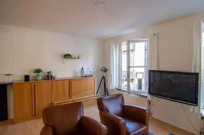 a living room with a flat screen tv and two chairs at Centre Hilversum, 20 minutes train to Amsterdam in Hilversum