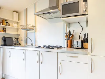 a kitchen with white cabinets and a microwave at Vlinder in Bergen