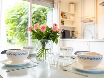 a table with plates and a vase of pink flowers at Vlinder in Bergen