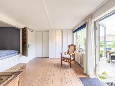 a room with a chair and a bed and a window at Vlinder in Bergen