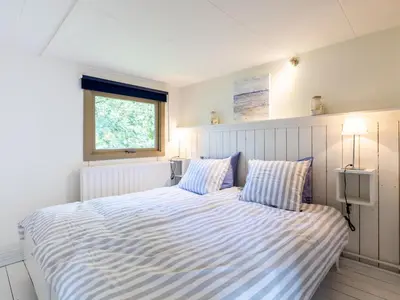 a bedroom with a large bed with striped sheets at Vlinder in Bergen