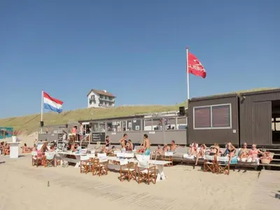 a group of people sitting in chairs on the beach at De egelhut in Bergen