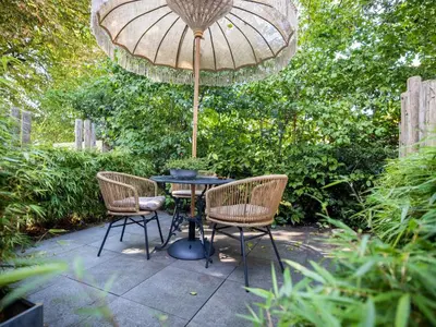 a patio with a table and two chairs and an umbrella at De egelhut in Bergen