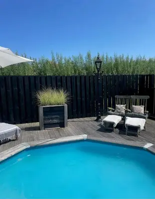 a swimming pool in a backyard with a black fence at De Koolschuur in Heerhugowaard