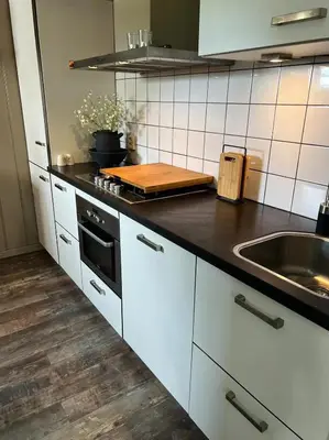 a kitchen with white cabinets and a black counter top at De Koolschuur in Heerhugowaard