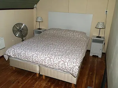 a bedroom with a bed and two tables with lamps at Paul en Lettie's Bed and Breakfast in Westbroek