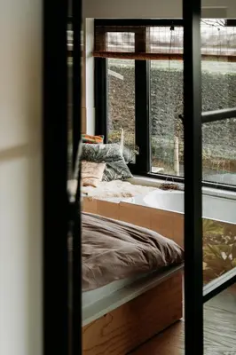a bedroom with a bed and a bath tub next to a window at Sfeervol Vakantiehuis - Badkuip met weids uitzicht - Markermeer - by Familie Buitenhuys holiday houses in Oosterleek