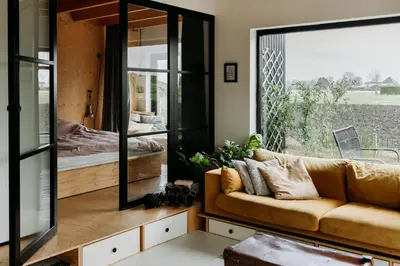 a living room with a couch and a large mirror at Sfeervol Vakantiehuis - Badkuip met weids uitzicht - Markermeer - by Familie Buitenhuys holiday houses in Oosterleek