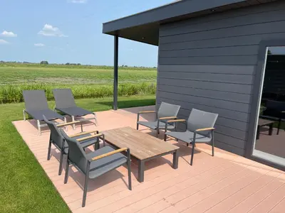 a deck with chairs and a table and a building at Miva in Leiderdorp